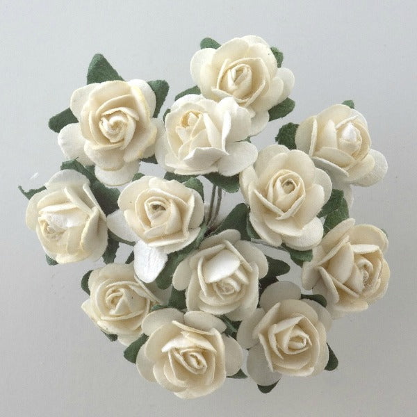 The Cream Paper Tea Roses Bunch of 12 by Perfect Tables features a bouquet of small, cream-colored paper tea roses arranged in a circular pattern against a light background. The roses are interspersed with green paper leaves, adding a touch of natural contrast to this perfect addition for craft projects or gift wrapping.