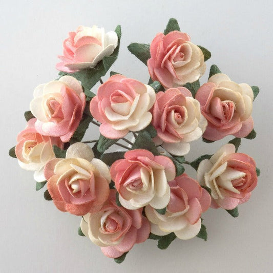 The Peach Paper Tea Roses Bunch of 12 by Perfect Tables features a tightly clustered bouquet of small, delicate paper tea roses in enchanting shades of pink, peach, and cream, interspersed with lush green leaves. Ideal for craft projects or gift wrapping, this arrangement radiates beautifully against a plain, light gray background.