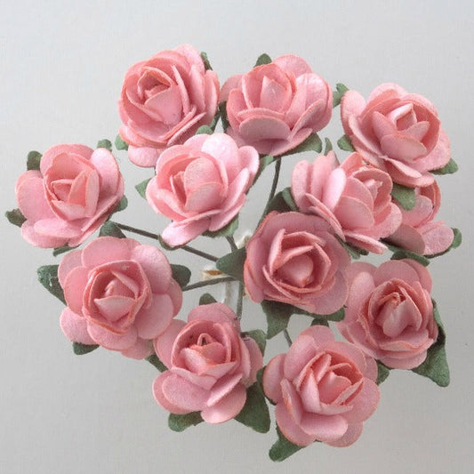 A close-up image of a bouquet featuring twelve delicate Pink Paper Tea Roses by Perfect Tables, with green leaves arranged in a circular pattern. The soft pink petals and lush green leaves create a harmonious, visually pleasing composition—perfect for elegant craft projects or gift wrapping ideas.
