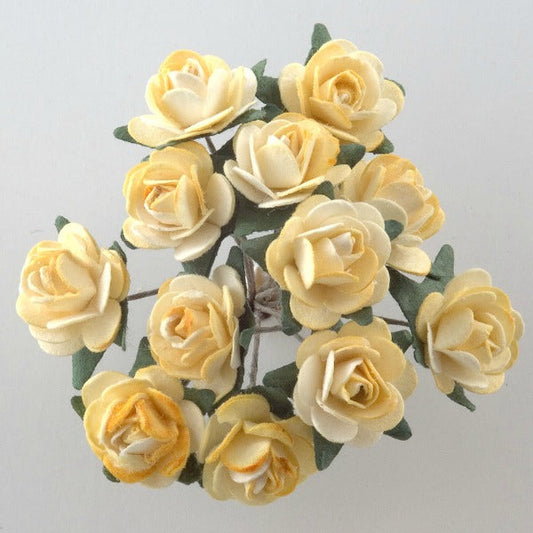 A small bouquet of delicate, light yellow paper tea roses with green leaves arranged in a circular pattern. The Yellow Paper Tea Roses Bunch of 12 from Perfect Tables has a soft and realistic appearance, suggesting careful craftsmanship or natural beauty. Perfect for craft projects or elegant gift wrapping, the plain white background draws focus to the roses.